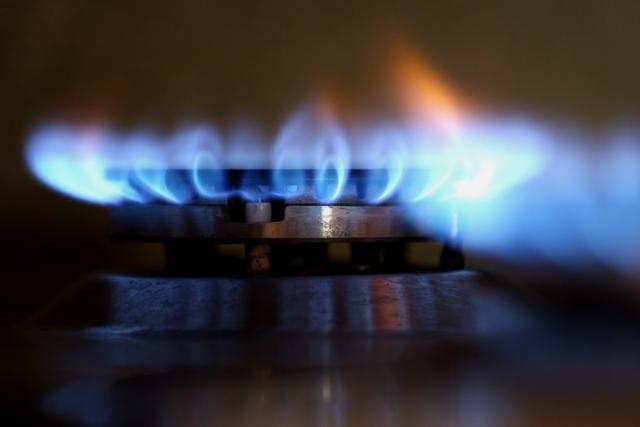 Closeup of a stovetop gas burner with blue flame
