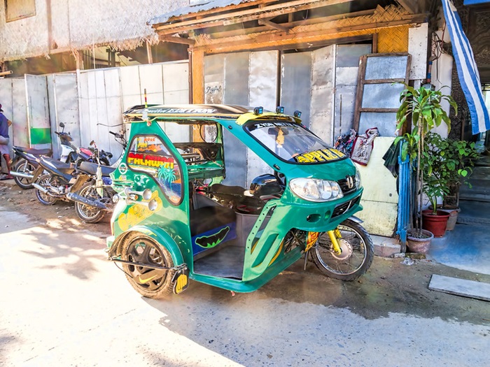 Colorful motorized tricycle parked next to a building